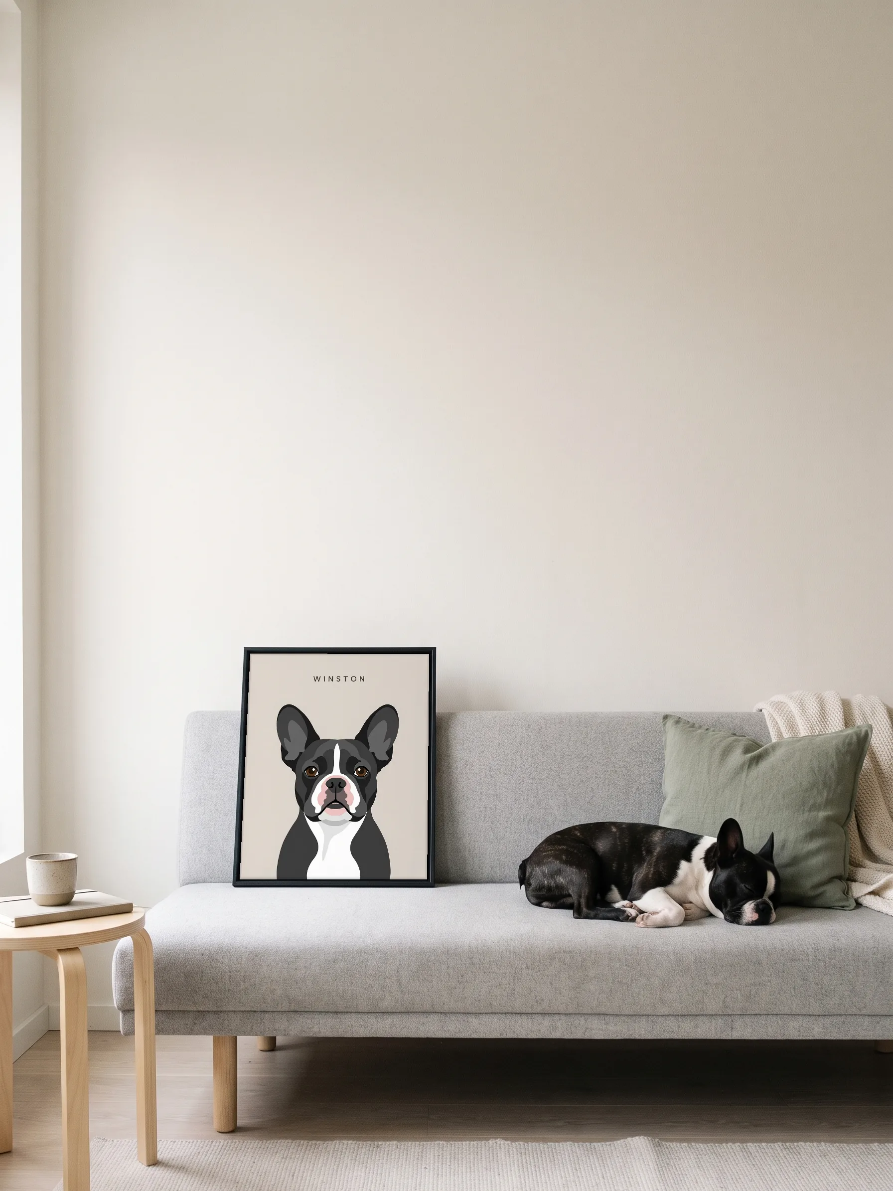 A black and white French bulldog asleep on a grey sofa beside its own minimalist portrait: a canvas in a slim black frame