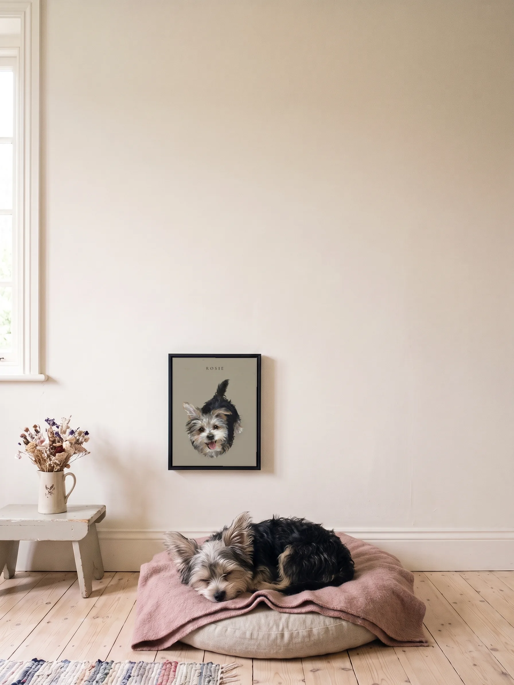 A small scruffy terrier asleep on a floor cushion under its own pastel portrait, a framed canvas on the wall