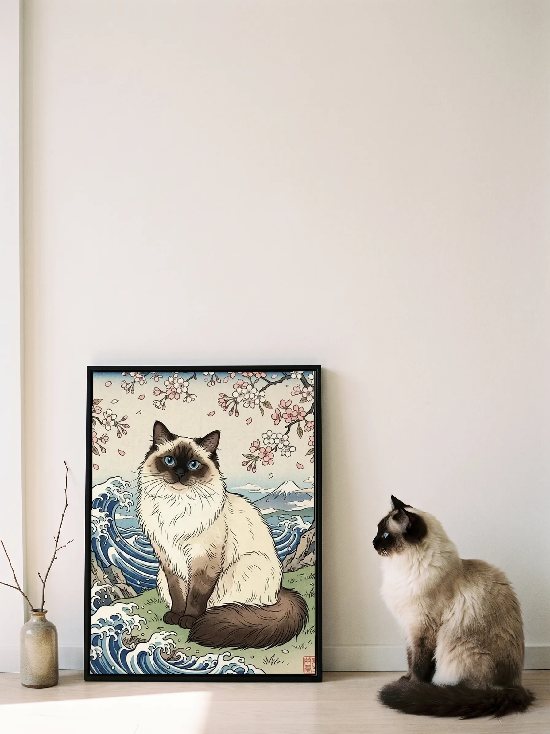 A ragdoll cat sitting in profile beside its own woodblock-style portrait: a canvas in a slim black frame leaning on a wall, sun on the floor