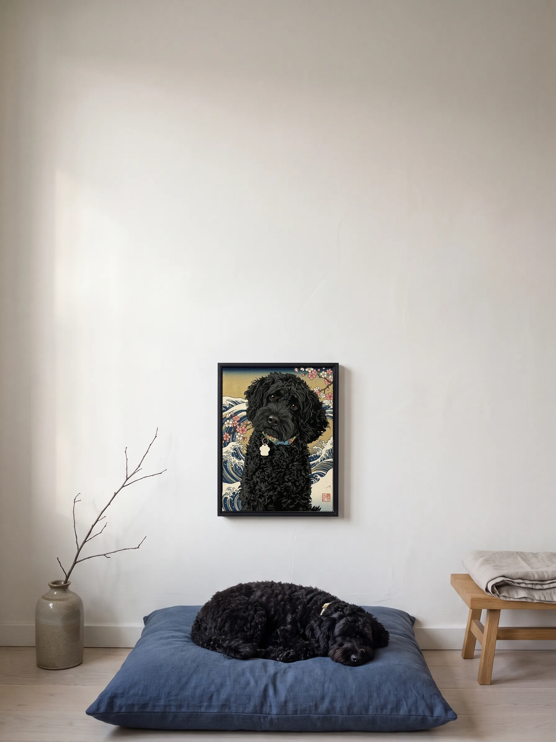 A small black curly-coated dog asleep on an indigo floor cushion under its own woodblock-style portrait, a framed canvas on the wall
